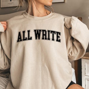 May include: A beige sweatshirt with the text "ALL WRITE" in black block letters.