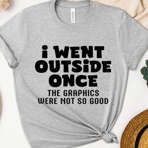 May include: Gray t-shirt with black text that reads "I went outside once. The graphics were not so good."