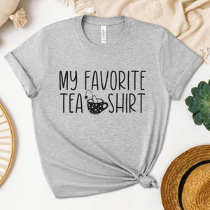 May include: Gray t-shirt with the text "My Favorite Tea Shirt" and a black and white illustration of a teacup with a tea bag.