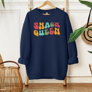 a blue sweatshirt with the words snack queen printed on it