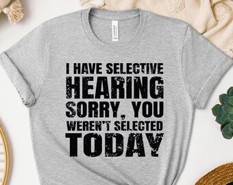 May include: A heather gray t-shirt with the text "I HAVE SELECTIVE HEARING SORRY, YOU WEREN'T SELECTED TODAY" in bold, black letters. The shirt has a crew neck and short sleeves.