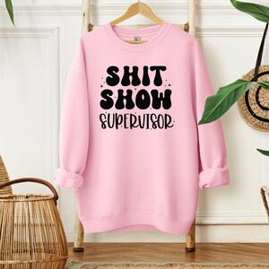 a pink sweatshirt hanging on a rack next to a potted plant