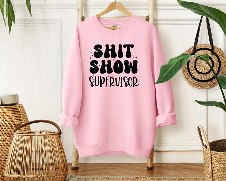 a pink sweatshirt hanging on a rack next to a potted plant