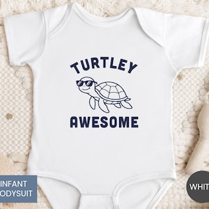 May include: A white infant bodysuit featuring a dark blue graphic of a turtle wearing sunglasses. The text "TURTLEY" is printed in dark blue above the turtle, and the word "AWESOME" is printed in dark blue below the turtle graphic.