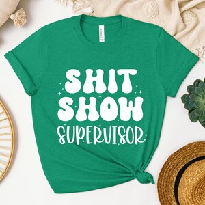 a green shirt that says shit show supervisor