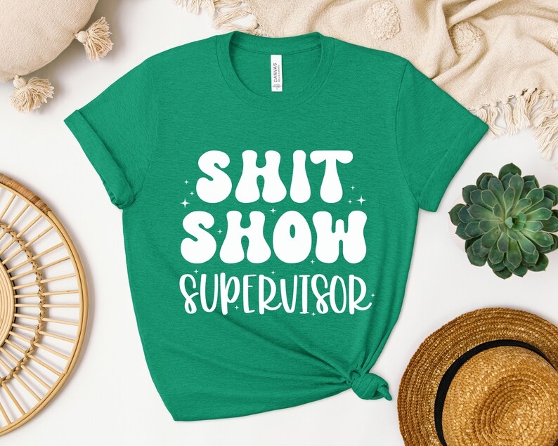 a green shirt that says shit show supervisor