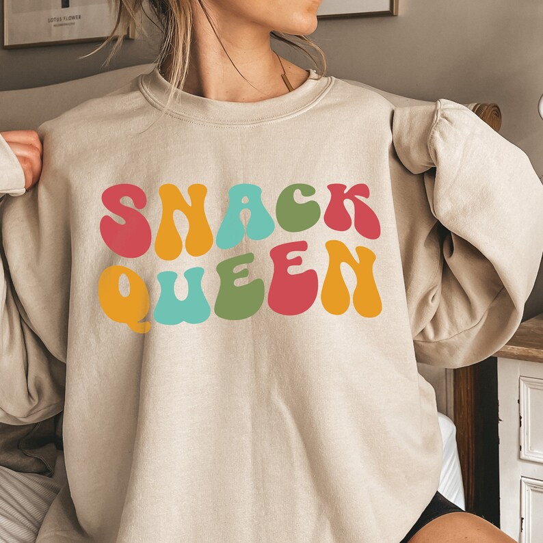 a woman wearing a sweatshirt that says snack queen