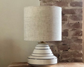 Table lamp in neutral colors, ceramic vase in special shape in white and black. Linen hood.