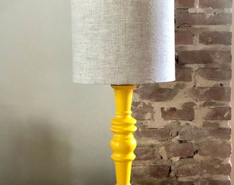 Lámpara de sobremesa con base de madera torneada vintage lacada en amarillo y pantalla de lino.