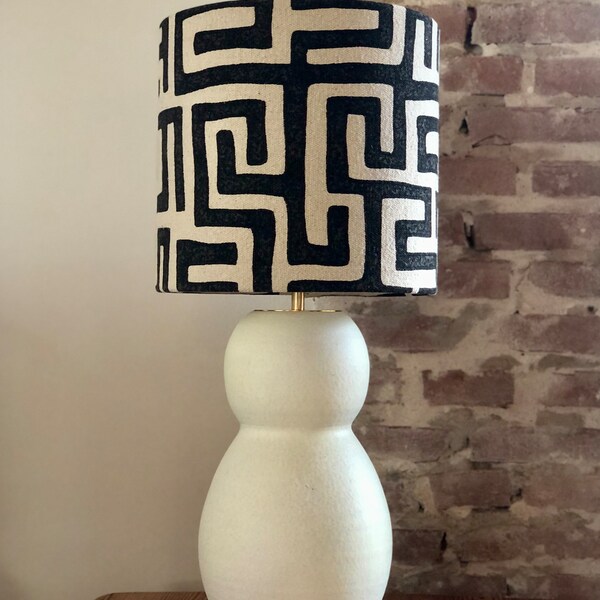 Lampe de table avec base en faïence mate et abat-jour en lin robuste avec motif décoratif ethnique noir. Moderne, avec un aspect chaleureux.