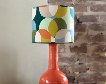 Cheerful, colorful table lamp with orange ceramic base and shade with circles