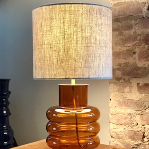 Table lamp made of orange glass with linen shade, retro, 70's style. Gold metal and brass details.