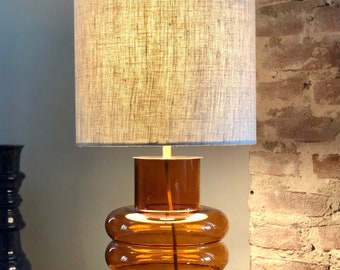 Table lamp made of orange glass with linen shade, retro, 70's style. Gold metal and brass details.