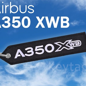 May include: Black airplane keychain with white text that reads "Airbus A350 XWB".