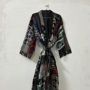 May include: A black quilted robe with a patchwork design featuring various colors and patterns. The robe has a tie belt and long sleeves.