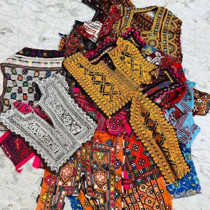 May include: A collection of colorful embroidered fabric scraps with intricate patterns and mirror embellishments. The fabric is a mix of different textures and colors, including orange, red, blue, green, and white.