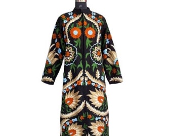 Puede incluir: Una larga chaqueta negra con intrincados bordados florales en tonos naranja, verde, azul y dorado. El bordado presenta un patrón repetitivo de flores y hojas estilizadas.