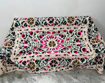 May include: A white cotton throw blanket with a floral embroidery design. The embroidery features pink, brown, and black flowers and leaves on a white background.