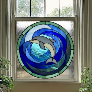 May include: Stained glass window art featuring a dolphin swimming in a swirling ocean of blues and greens. The dolphin is gray and white, set against a backdrop of water and waves. The artwork is framed in a window.