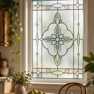 Könnte beinhalten: Ein rechteckiges Fenster mit einer dekorativen Buntglaseinlage, die ein zentrales Blumenmotiv in Salbeigrün, Creme und klarem Strukturglas zeigt. Das Design ist von dunklen Bleilinien und geometrischen Akzenten umrahmt.