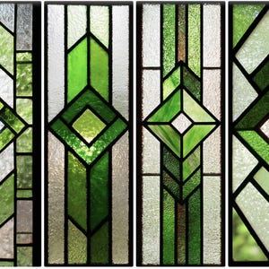 Puede incluir: Cuatro paneles de vidrieras con diseños geométricos en tonos verdes y vidrio transparente. Cada panel presenta una forma de diamante central y líneas verticales e inclinadas, enmarcadas por bordes negros. Los paneles están dispuestos uno al lado del otro.