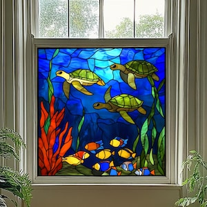 May include: Stained glass window panel featuring an underwater scene. Three green sea turtles swim in a deep blue ocean with colorful fish and seaweed. The window is framed in white and set in a window.
