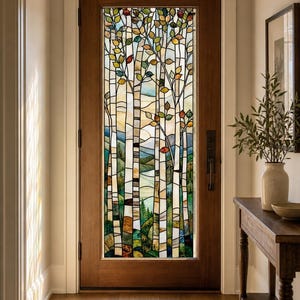 Può includere: Una porta in legno dotata di un grande pannello rettangolare in vetro colorato. Il vetro raffigura una scena boschiva con tronchi d'albero alti e sottili e foglie colorate nelle tonalità del verde, giallo e arancione, su uno sfondo di colline.