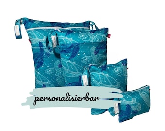 May include: Set of four blue reusable zippered bags with a sea turtle pattern. The bags are different sizes and have a white zipper. The largest bag has a red zipper pull. The text "personalisierbar" is written in black on a white background.