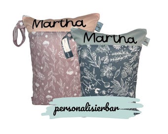 May include: Two reusable wet bags with floral patterns and the name "Martha" printed on them. The bags are personalized and have a drawstring closure.