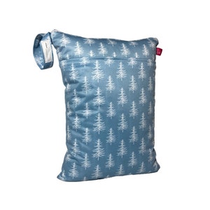 Könnte beinhalten: Eine blaue, wiederverwendbare Tasche mit einem weißen Kiefernbaum-Muster. Die Tasche hat einen Reißverschluss, eine kleine Tasche und eine Stoffschlaufe mit Klettverschluss. Ein kleines rosa Etikett ist an der Seite befestigt.