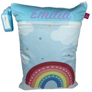 Könnte beinhalten: Eine wiederverwendbare, blaue und weiße Feucht-Tasche mit einem Regenbogen- und Wolken-Design. Die Tasche hat einen Reißverschluss und ein Etikett mit der Aufschrift "Emilia".