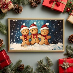 May include: Three gingerbread men with red hats and scarves stand together in a snowy winter scene. The gingerbread men are smiling and holding hands. The background is a dark blue sky with white snowflakes.