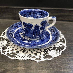 Peut inclure: Une tasse à thé et une soucoupe en porcelaine bleue et blanche avec un motif chinois traditionnel. La tasse et la soucoupe sont décorées d'un motif bleu et blanc de fleurs, d'oiseaux et d'une pagode.