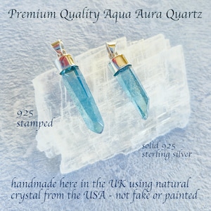 May include: Two Aqua Aura Quartz pendants with silver-coloured metal caps. The pendants are a light blue colour and are displayed on a white crystal formation. Text on the image reads "Premium Quality Aqua Aura Quartz" and "925 stamped".