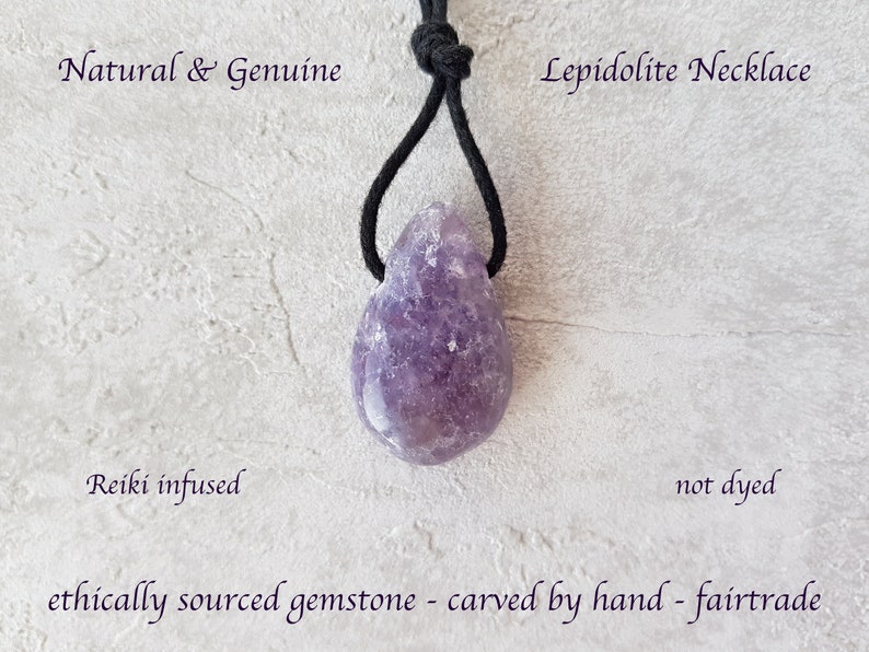 Puede incluir: Un collar de lepidolita natural con una gema p&uacute;rpura en forma de l&aacute;grima. El collar cuelga de un cord&oacute;n negro. El texto en la imagen dice: "Natural & Genuine", "Lepidolite Necklace", "Reiki infused", "not dyed" y "ethically sourced gemstone - carved by hand - fairtrade".