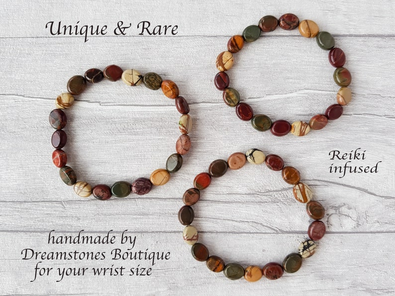 Puede incluir: Tres pulseras hechas a mano con piedras ovaladas multicolores en tonos rojos, marrones, verdes y crema. Las pulseras se exhiben sobre una superficie clara con vetas de madera. El texto de la imagen dice "Unique & Rare" y "Reiki infused".