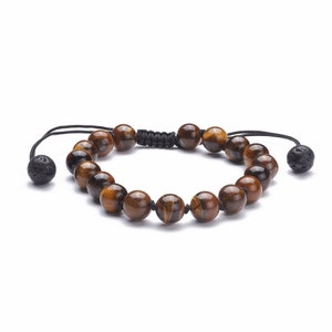 May include: A bracelet made of brown and gold tiger's eye beads. The round beads are strung on a black cord with adjustable ends. The bracelet has black lava stone accents.