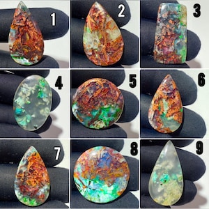May include: A collection of nine polished gemstones labeled one through nine, featuring varied shapes including teardrops, ovals, and rectangles. The stones display intricate patterns of copper-colored metallic inclusions and vibrant green flecks.
