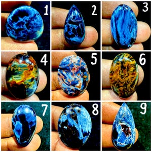 May include: A collection of nine polished gemstones labelled one through nine, featuring varied patterns of deep blue, black, and golden-brown swirls. Each stone displays a unique, marbled appearance with smooth, rounded, oval, or teardrop shapes.