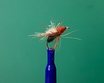 May include: A brown, black, and white fly fishing lure with a red head, tied to a blue fishing rod holder.