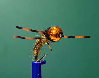 May include: A close-up of a brown and gold fly fishing lure with a copper bead head and black and brown wings.