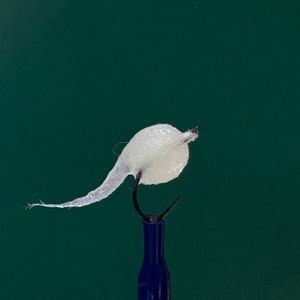May include: A white fly fishing lure with a translucent body and a long, thin tail.