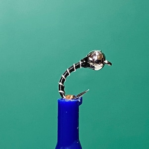 May include: A black and silver fly fishing lure with a bead head.