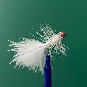 May include: A white fly fishing lure with a pink bead head and purple iridescent fibres. The lure is mounted on a blue fishing rod.