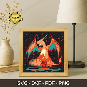 May include: A framed print featuring a stylized illustration of a dragon in shades of orange, red, and teal against a black background. The print is in a light wood frame. The bottom of the frame displays the text "SVG - DXF - PDF - PNG".