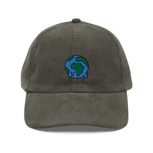 Puede incluir: Una gorra de béisbol de pana verde oscuro con una imagen bordada de una Tierra derritiéndose en azul y verde.