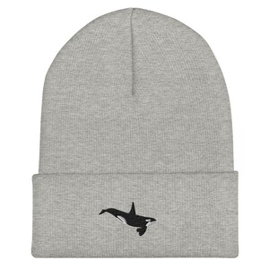 Op de afbeelding: Grijze beanie met een geborduurd orka-ontwerp in zwart en wit.