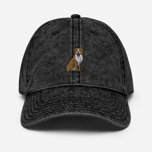 May include: A black vintage washed denim baseball cap with an embroidered image of a brown and white dog with a pink tongue sticking out.