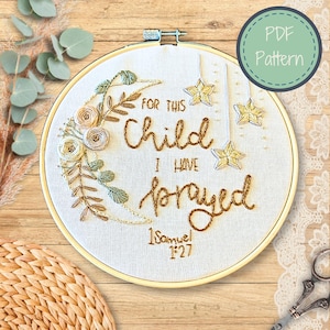 Puede incluir: Arte de bordado en aro con una luna creciente, estrellas y detalles florales. El texto dice "Por este niño he orado 1 Samuel 1:27".