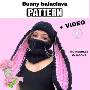 May include: Black and pink bunny balaclava pattern with the word "PATTERN" in bold white letters. The balaclava has long, floppy ears with pink interiors and silver chain accents. The image also includes a ball of pink yarn and the text "+ VIDEO".